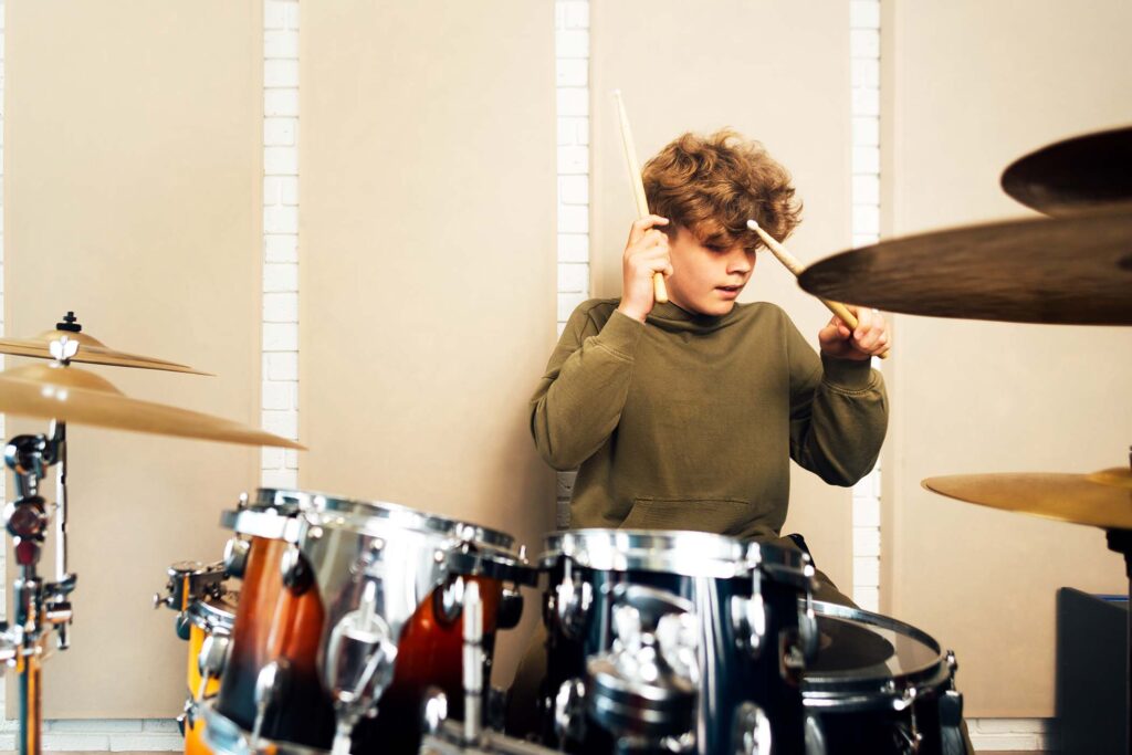 boy-banging-on-a-drum-kit-lesson-at-the-music-sch-53E7LRC.jpg